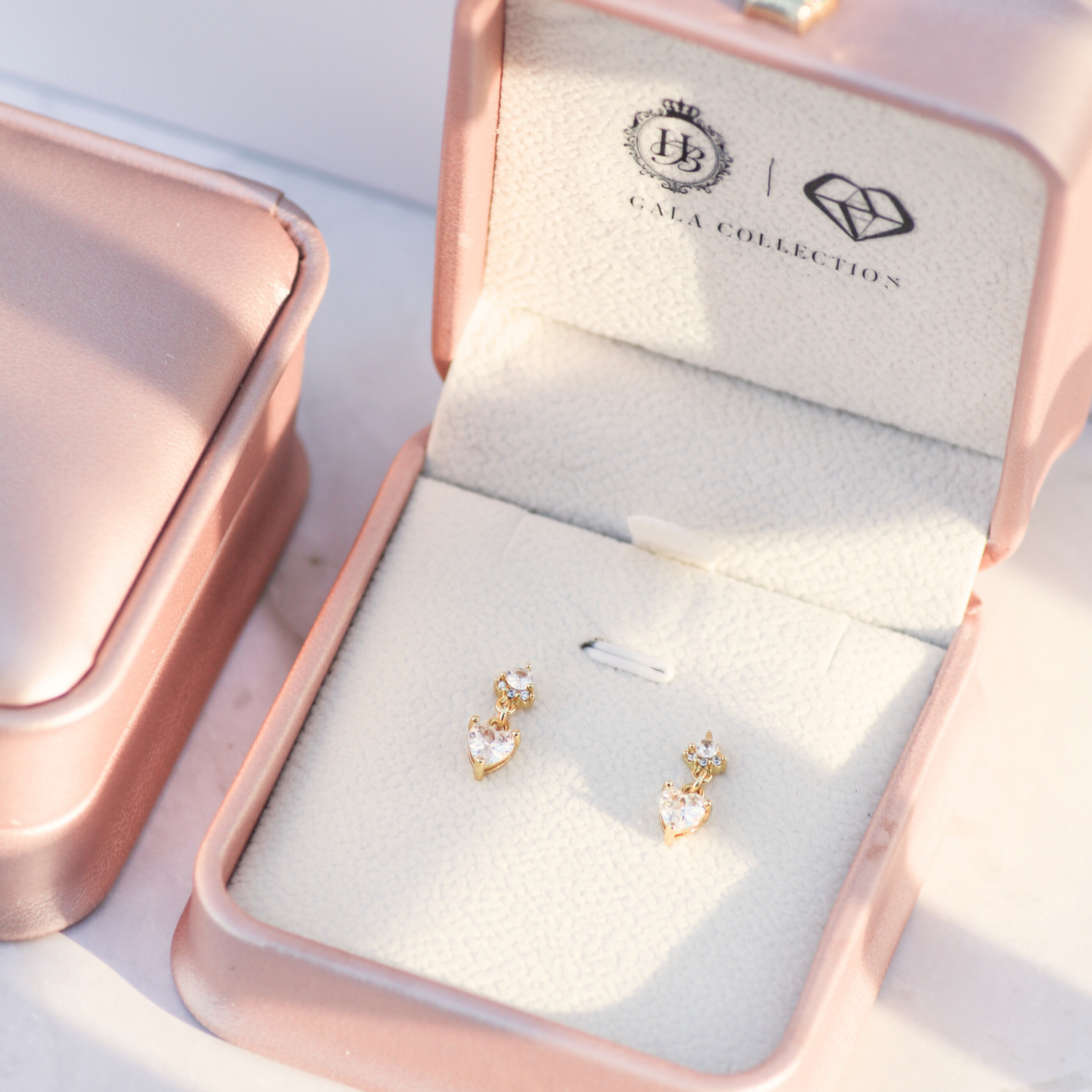 Gold earrings in a jewelry box with 'Gala Collection' branding.