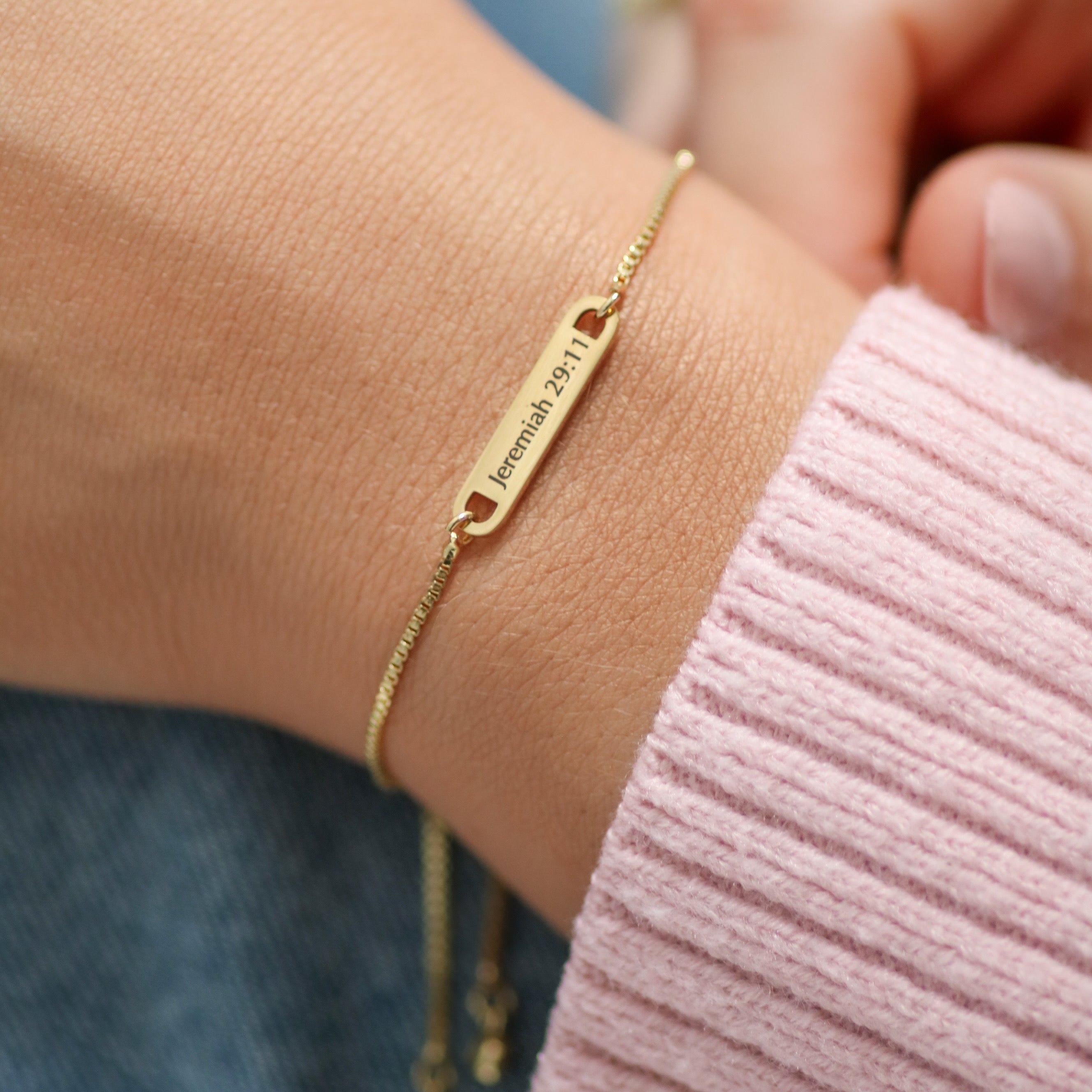 Gold bracelet JEREMIAH 29:11 with engraved text on a wrist against a blurred background