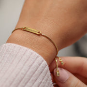 Gold bracelet God Provides, Trust His Timing on a wrist with a blurred background