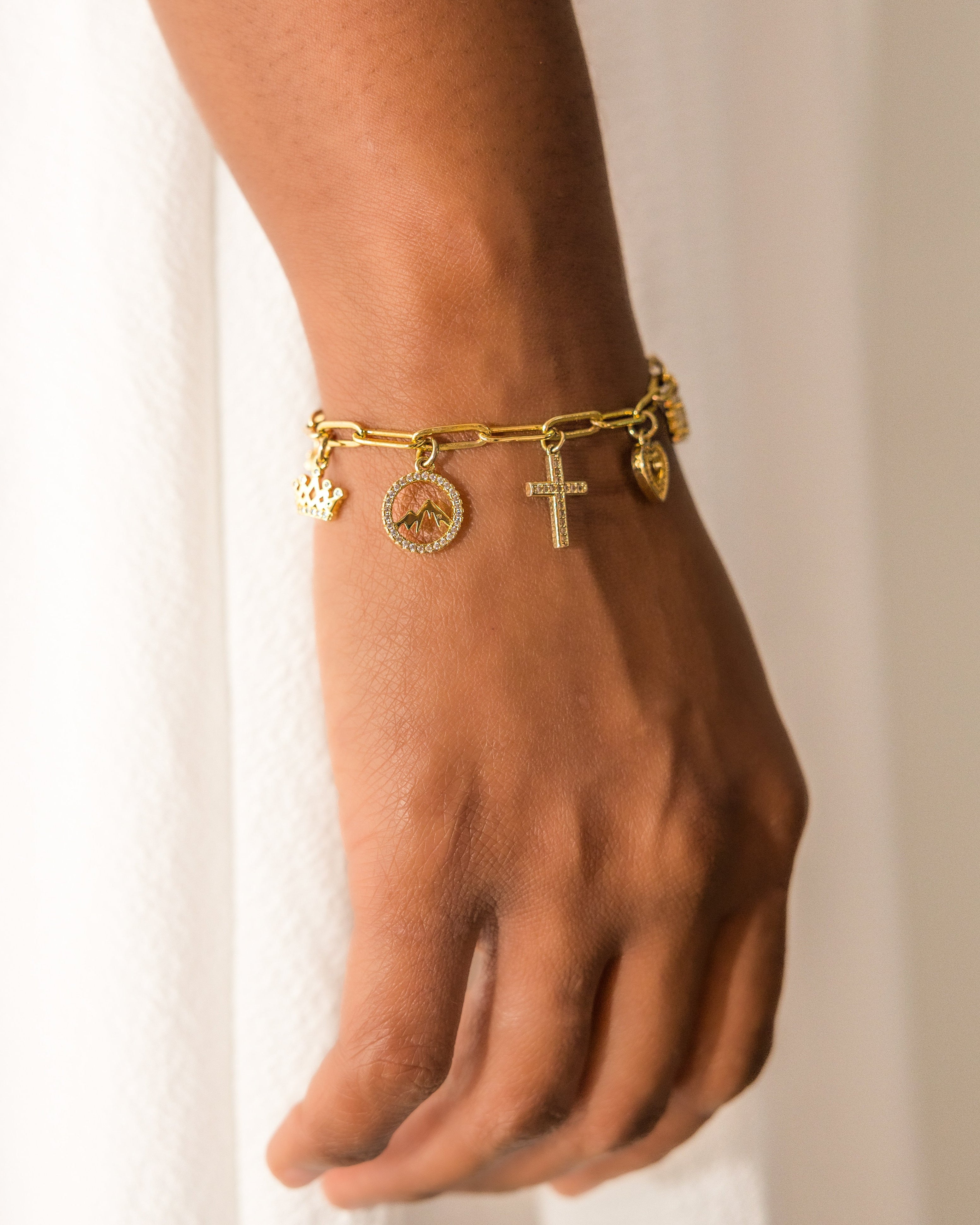 Gold bracelet with charms on a wrist against a white background